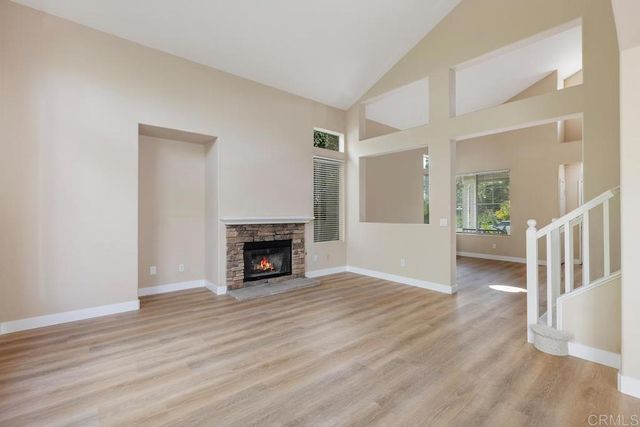 an empty room with wooden floor fireplace and windows