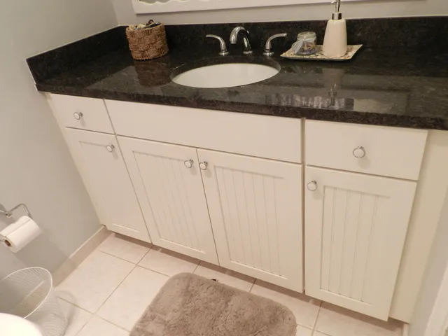 a bathroom with a granite countertop sink a mirror and vanity