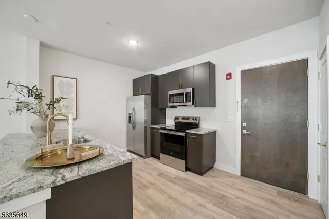 a kitchen with stainless steel appliances kitchen island granite countertop a sink and refrigerator