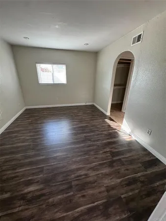 an empty room with wooden floor fan and windows
