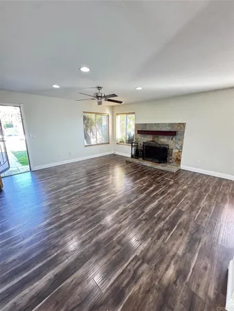 an empty room with wooden floor and kitchen view