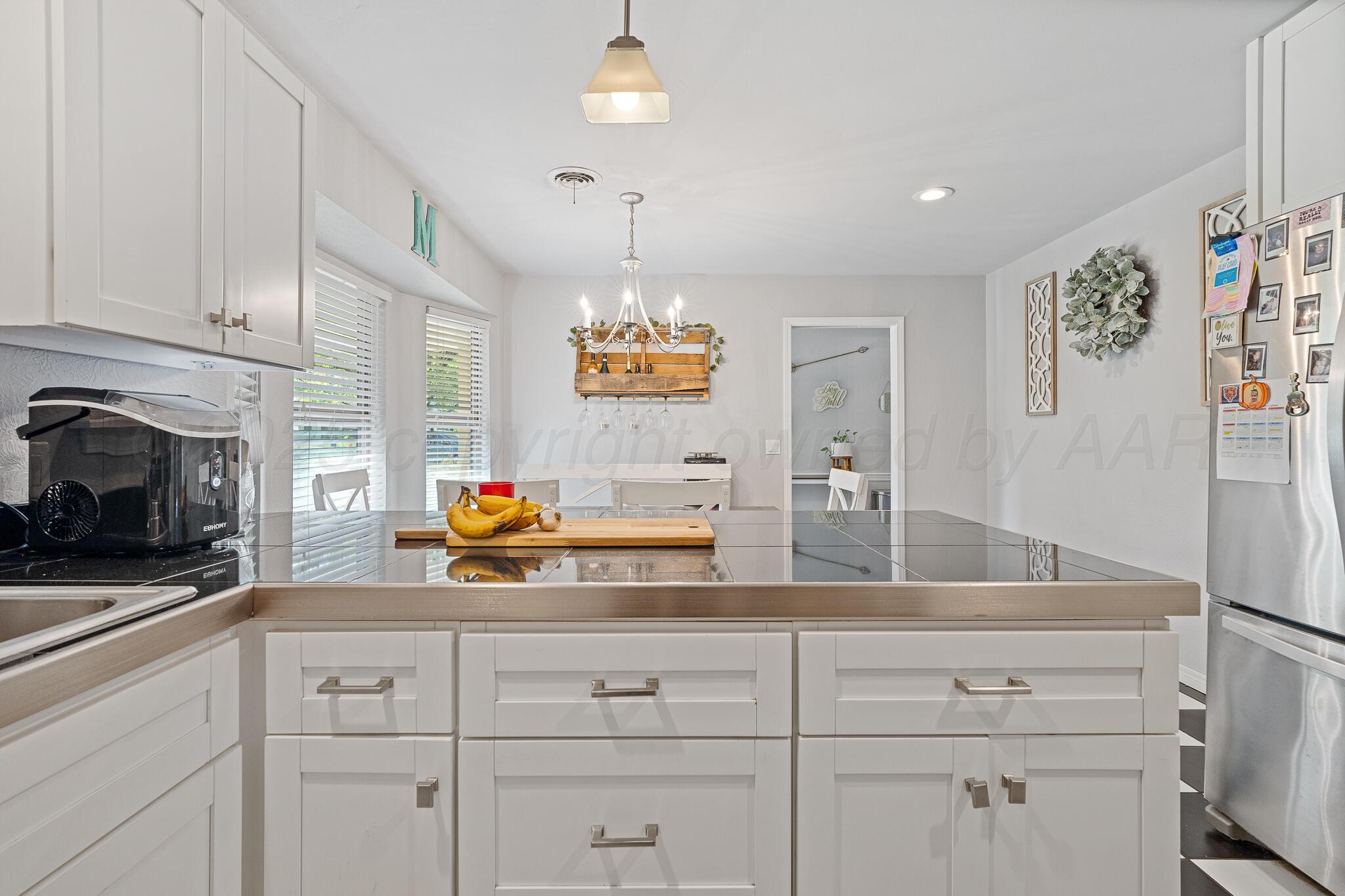 7602 Canode Drive Amarillo, TX 79121 - Photo 12 of 26 a kitchen with white cabinets and chandelier