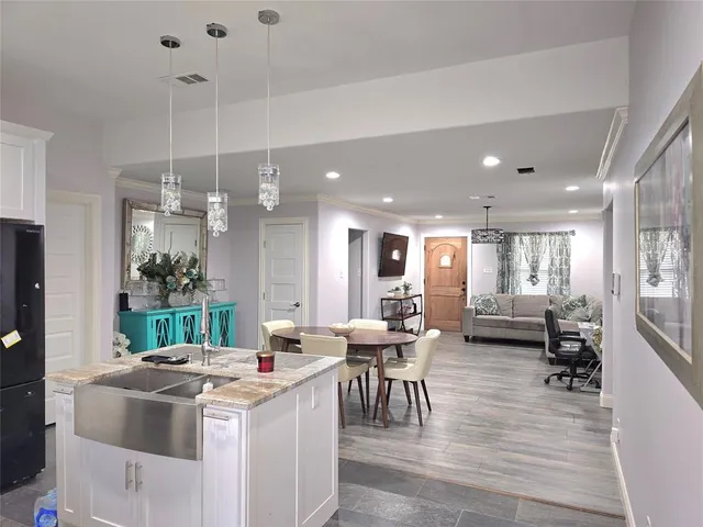 a kitchen with kitchen island a stove a dining table chairs and white cabinets