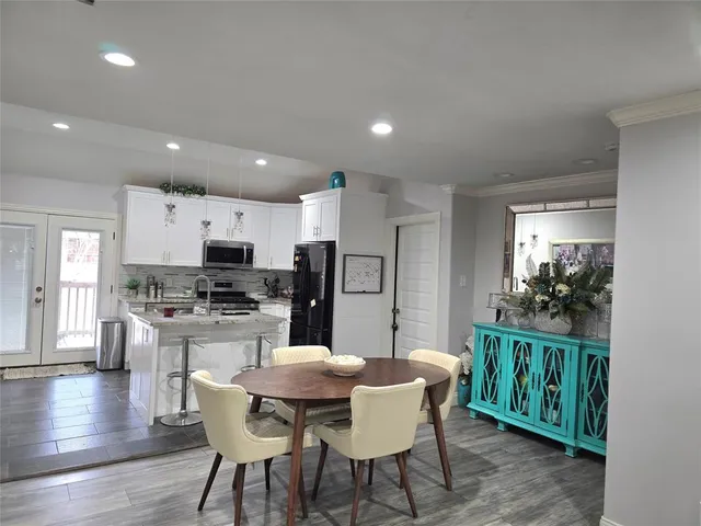 a kitchen with stainless steel appliances kitchen island granite countertop a dining table chairs and refrigerator