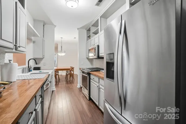 a kitchen with stainless steel appliances granite countertop a refrigerator a stove a sink and a dining table with wooden floor