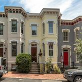 a front view of a building with lot of cars and trees