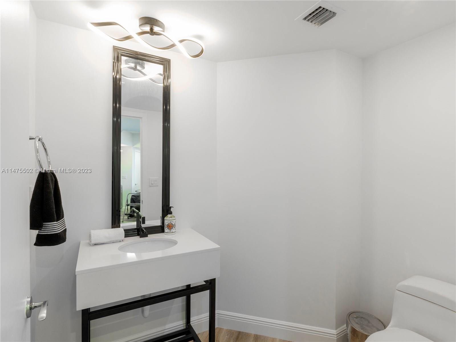 400 Alton Road, Unit 1104 Miami Beach, FL 33139 - Photo 16 of 27 a bathroom with a toilet a sink and mirror