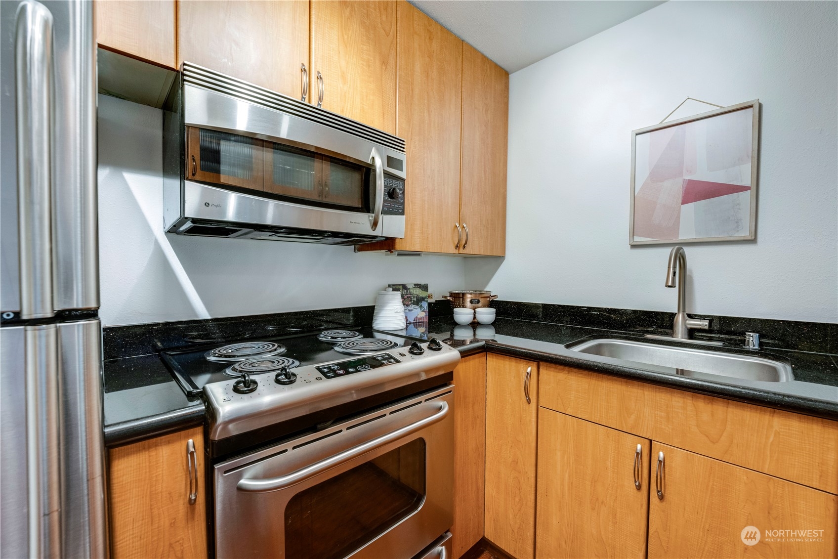 1105 Spring Street, Unit 309 Seattle, WA 98104 - Photo 13 of 39 a kitchen with stainless steel appliances granite countertop a sink stove and microwave