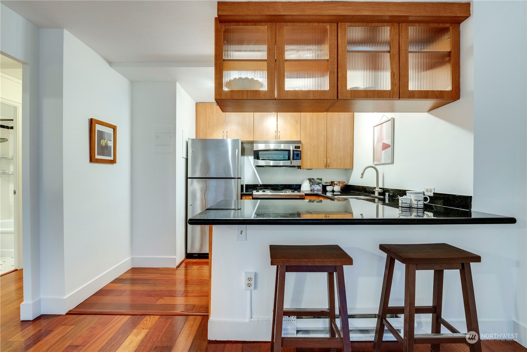 1105 Spring Street, Unit 309 Seattle, WA 98104 - Photo 10 of 39 a kitchen with stainless steel appliances granite countertop a table chairs in it and wooden floors