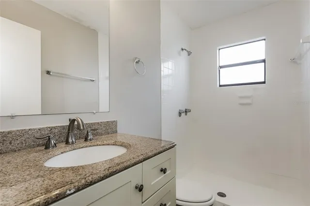 a bathroom with a granite countertop sink toilet and mirror