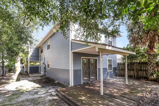 a backyard of a house with large trees and outdoor seating