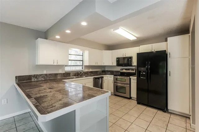 a kitchen with kitchen island a counter top space cabinets and stainless steel appliances