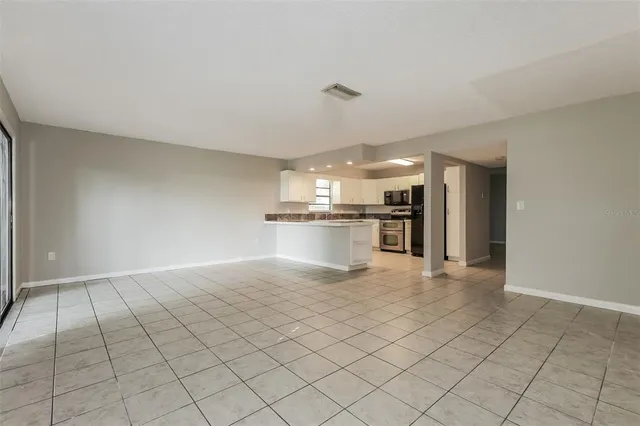 a view of a electric appliances in kitchen and empty room with wooden floor