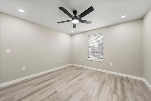 an empty room with ceiling fan and window