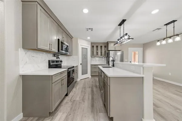 a kitchen with stainless steel appliances kitchen island a large counter space a sink and a refrigerator