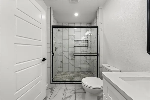 a bathroom with a granite countertop toilet a sink and a shower