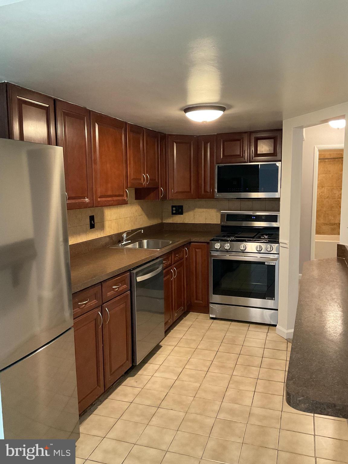 4509 Romlon Street, Unit 102 Beltsville, MD 20705 - Photo 2 of 22 a kitchen with stainless steel appliances granite countertop a stove a sink and a refrigerator