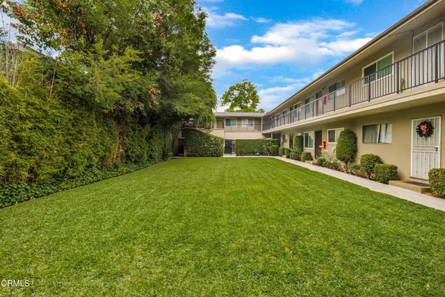 a view of house with a big yard and large trees