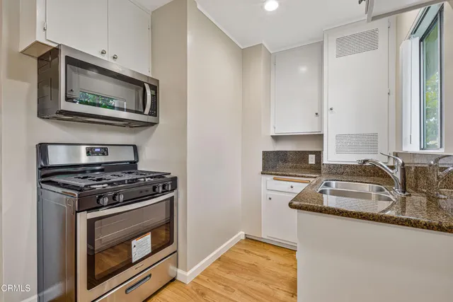 a kitchen with granite countertop stainless steel appliances a stove microwave and sink