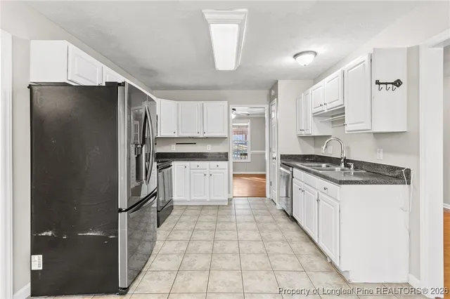 a kitchen with stainless steel appliances granite countertop a refrigerator a sink and white cabinets