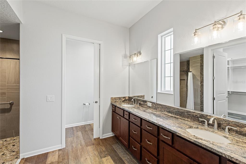 11202 Roz Way Oxford, FL 34484 - Photo 24 of 44 a bathroom with a granite countertop double vanity sink and mirror