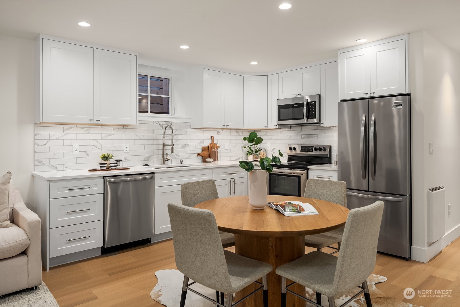 706 North 76th Street Seattle, WA 98103 - Photo 30 of 38 a kitchen with stainless steel appliances granite countertop a dining table chairs refrigerator and cabinets