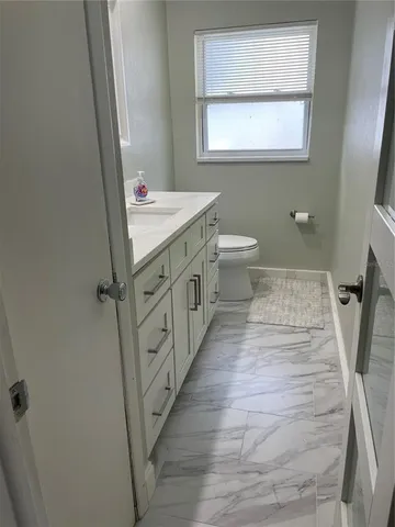 a bathroom with a sink a toilet a mirror and a window