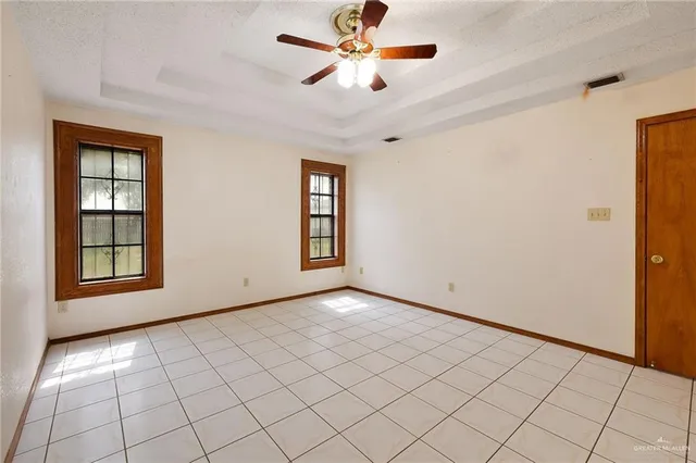 a view of an empty room with window and chandelier fan