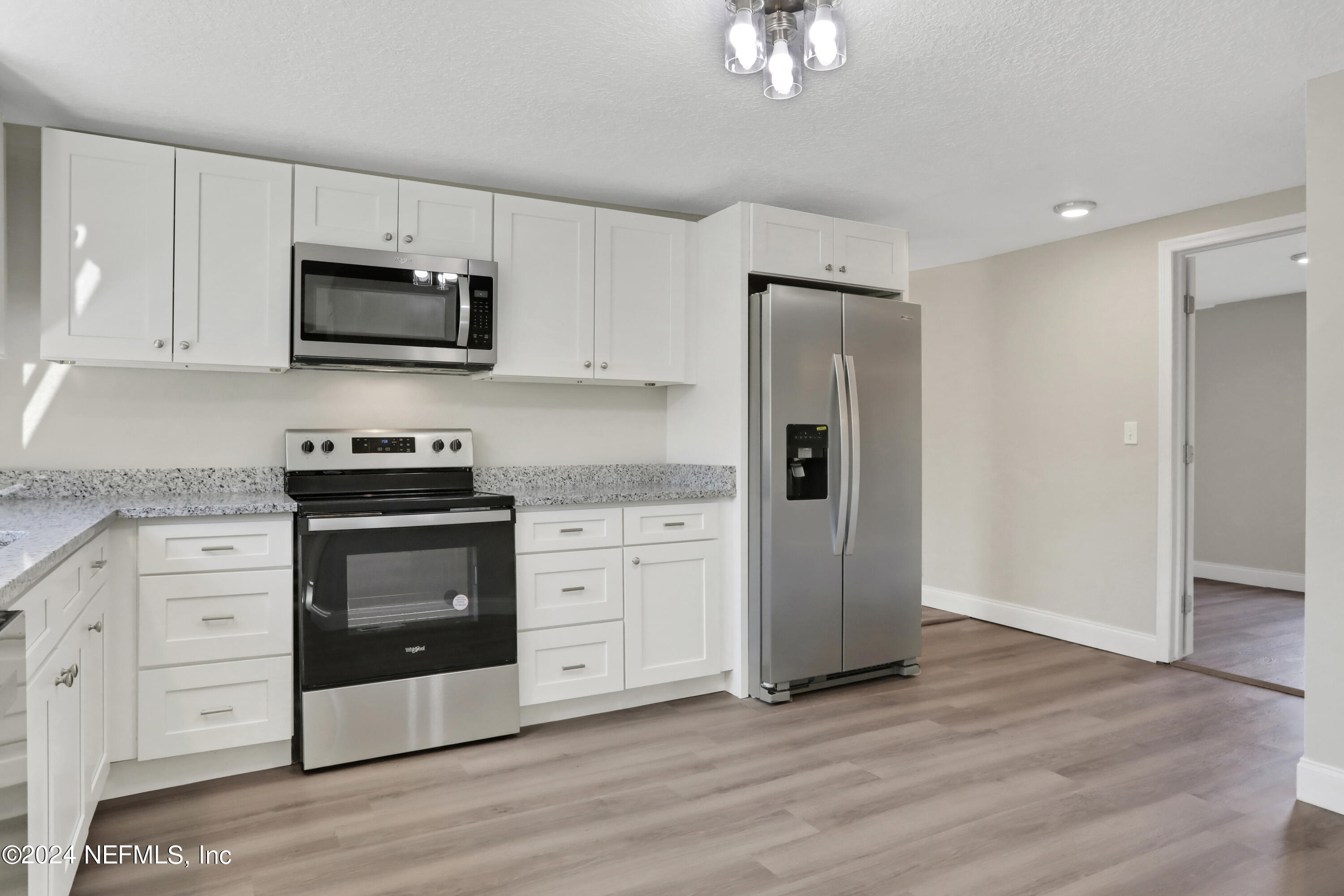 54057 Bea Road Callahan, FL 32011 - Photo 8 of 29 a kitchen with white cabinets stainless steel appliances and wooden floor