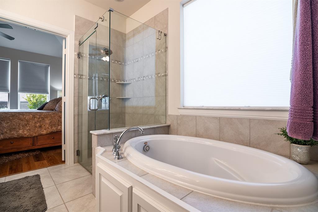 1213 Sea Island Road Aubrey, TX 76227 - Photo 27 of 36 Relax in the luxurious oval garden tub with a frosted window that fills the primary bathroom with soft, natural light