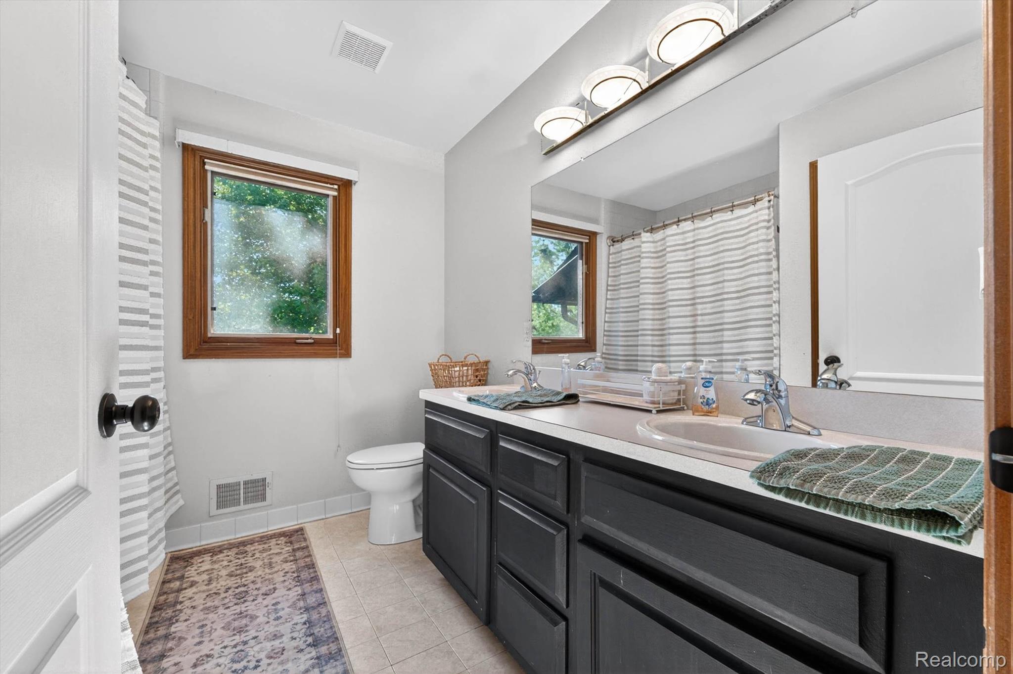 371 Lone Pine Circle Rochester, MI 48307 - Photo 30 of 59 Dual vanity with white countertop, chrome fixtures, and dark cabinetry