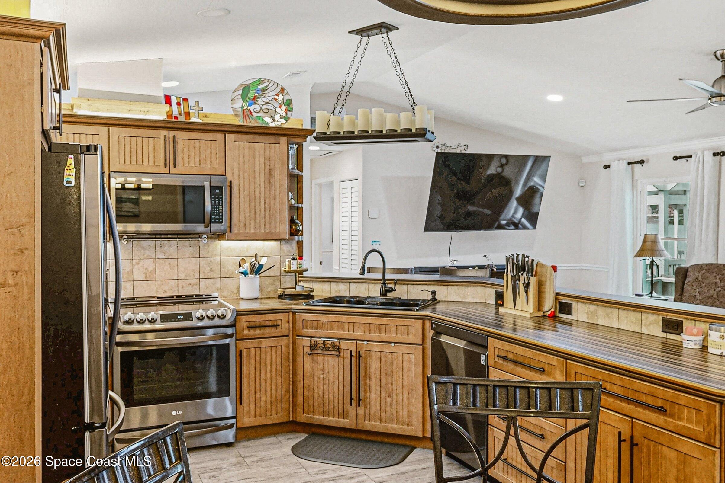 413 Orlov Road Northwest Palm Bay, FL 32907 - Photo 16 of 63 a kitchen with stainless steel appliances a stove a sink and a microwave