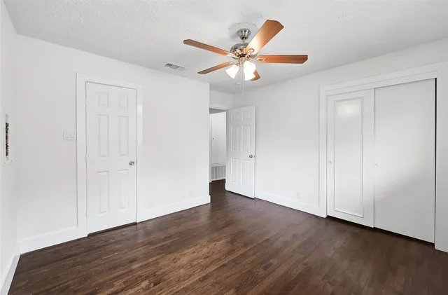 an empty room with wooden floor closet and ceiling fan