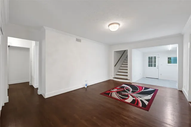 a view of an empty room with wooden floor and stairs