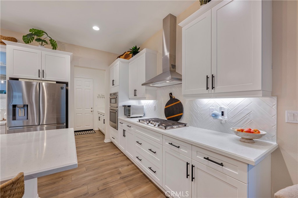 4124 Cameron Way Corona, CA 92883 - Photo 28 of 76 a kitchen with stainless steel appliances kitchen island granite countertop a refrigerator a stove and a sink