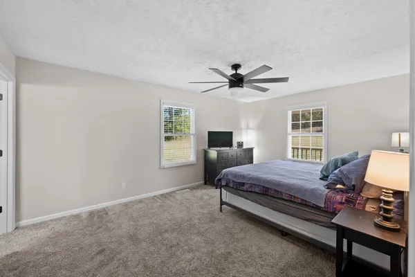 a bedroom with a bed a chair and a large window