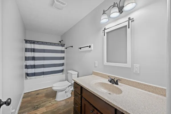 a bathroom with a granite countertop sink toilet a mirror and shower