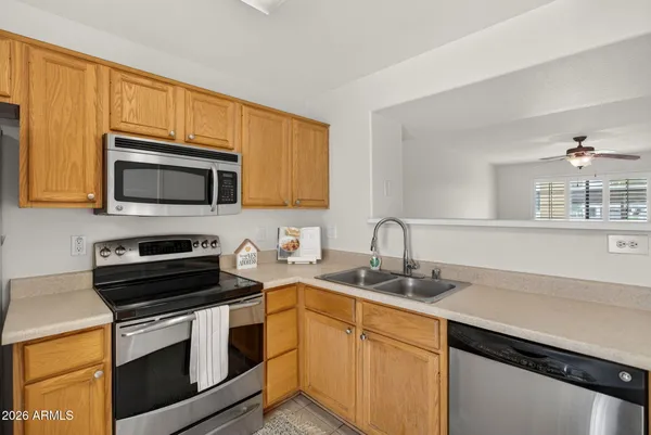 a kitchen with stainless steel appliances a microwave a stove a refrigerator cabinets and a window