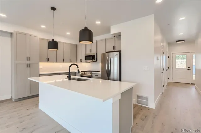 a view of a kitchen with stainless steel appliances kitchen island a refrigerator and a sink