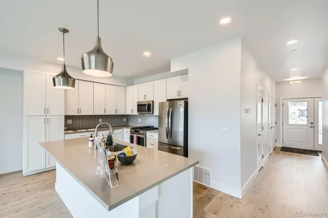 a kitchen with stainless steel appliances granite countertop a sink a refrigerator and a stove