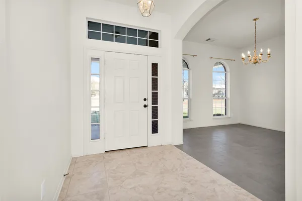 an empty room with chandelier fan and windows