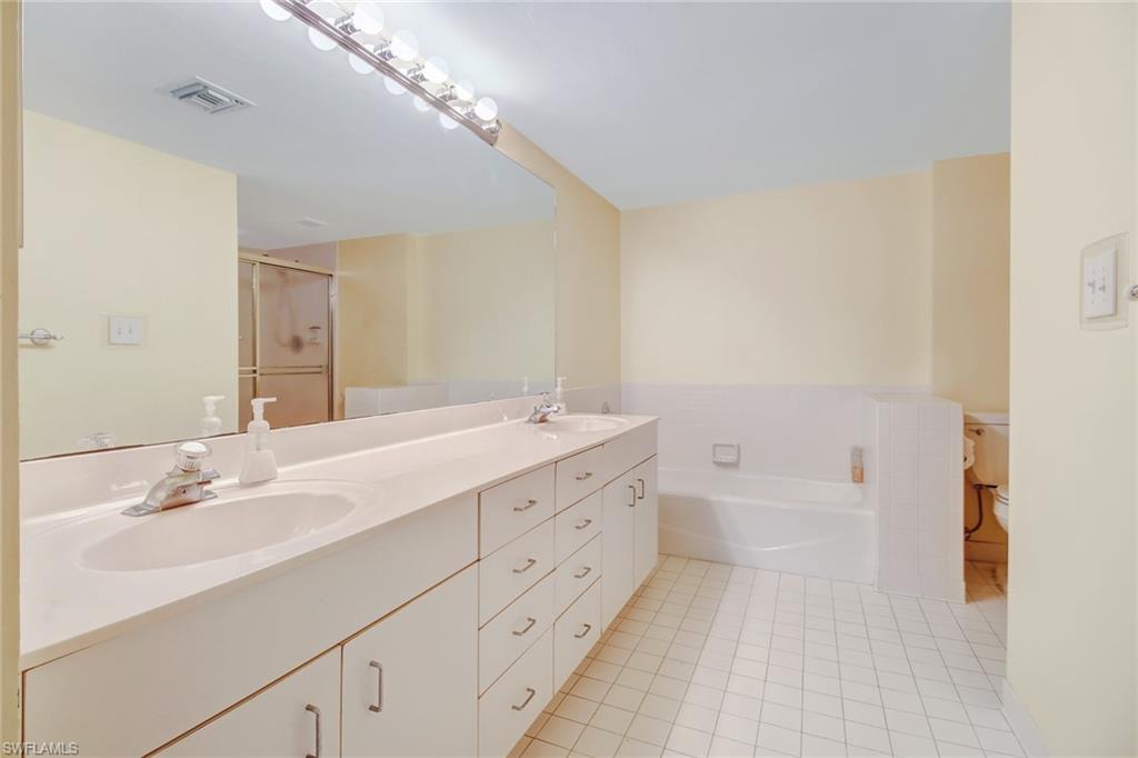 5635 Turtle Bay Drive, Unit I10 Naples, FL 34108 - Photo 16 of 25 a bathroom with a double vanity sink a mirror and a bathtub