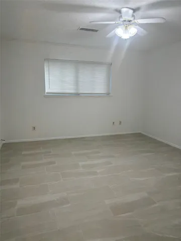 an empty room with a chandelier fan and windows