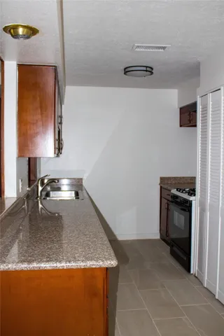 a kitchen with granite countertop a sink stove and refrigerator
