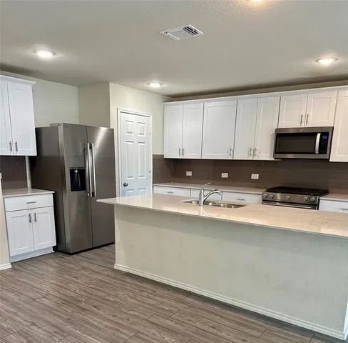 a view of a livingroom with a kitchen counter tops and wooden floor