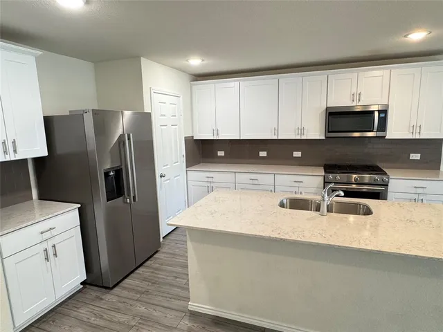 a kitchen with stainless steel appliances a refrigerator and a stove top oven