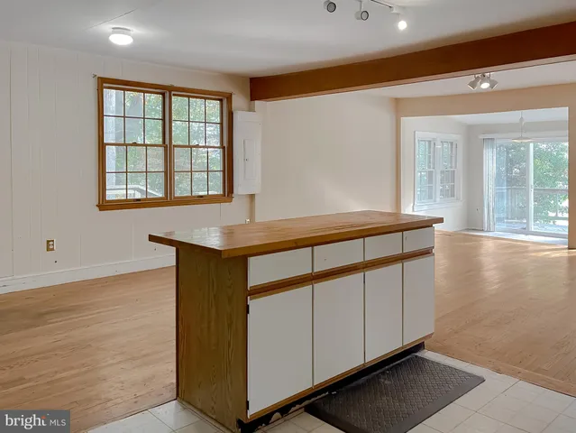 a view of kitchen and empty room with wooden floor
