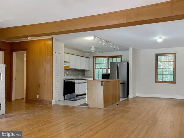 a view of an empty room with wooden floor and a fireplace