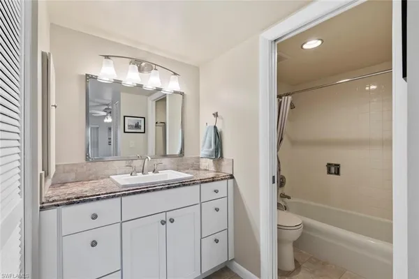 a bathroom with a granite countertop sink toilet and shower