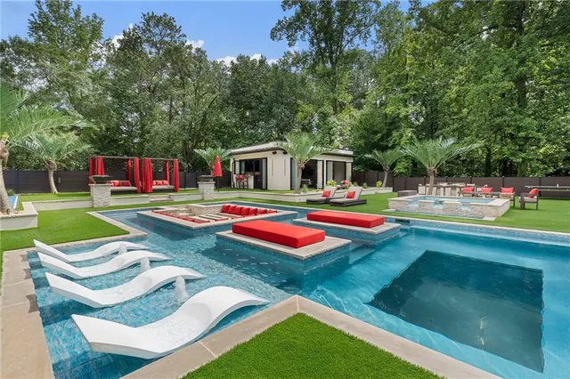 swimming pool with lawn chairs and large trees
